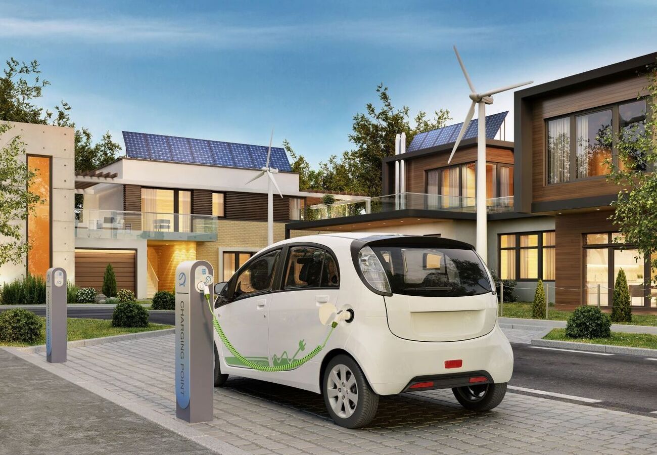 Aufladen eines Elektroautos an einer Ladestation vor modernen, umweltfreundlichen Häusern mit Photovoltaikanlagen